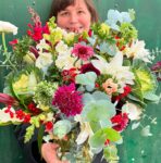 a woman holding a bouquet of colorful flowers