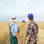 A pair of farmers standing in a field looking at a tractor