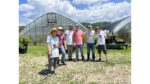A group of farmer scientists standing in front of a High Tunnel system