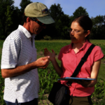A man and a woman talking in a field about information on an iPad