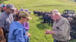Grazers learn about forage-based production in a green field with cows in the back